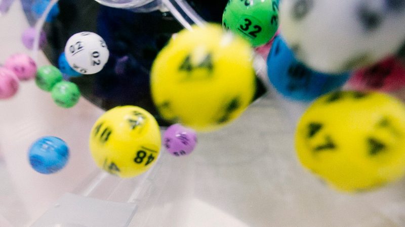 Numbered lottery balls tumbling inside a clear draw machine, several numbers legible